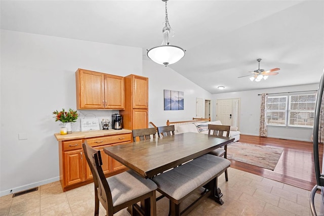 dining space featuring baseboards, visible vents, vaulted ceiling, and a ceiling fan