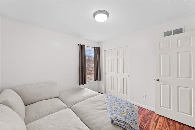 bedroom with baseboards, a closet, visible vents, and wood finished floors