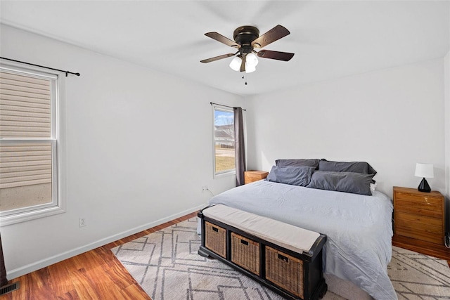 bedroom with ceiling fan, wood finished floors, visible vents, and baseboards