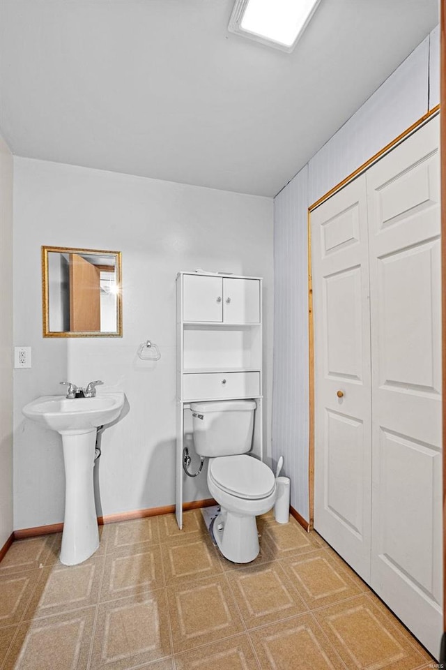 bathroom with toilet, baseboards, and a sink