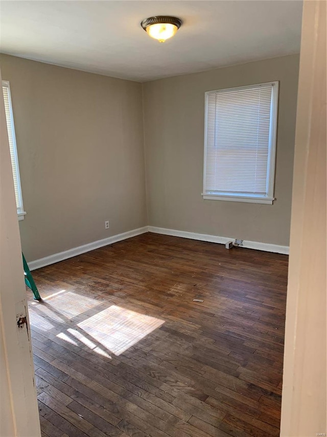 empty room with dark wood-type flooring and baseboards