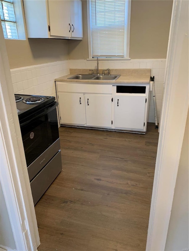 kitchen featuring stainless steel electric stove, white cabinets, and a sink