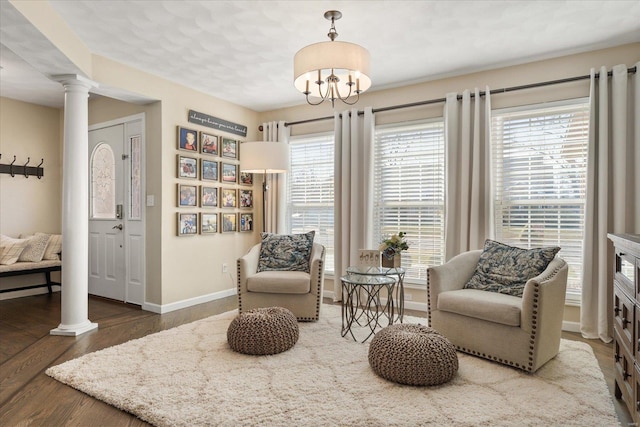 living area featuring ornate columns, baseboards, a wealth of natural light, and wood finished floors