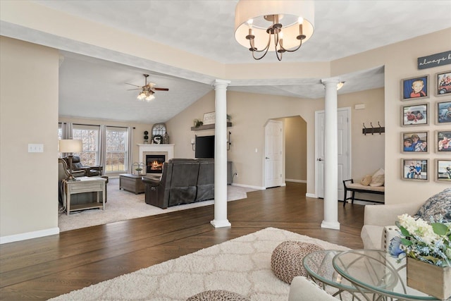 living area featuring a ceiling fan, a glass covered fireplace, ornate columns, and wood finished floors