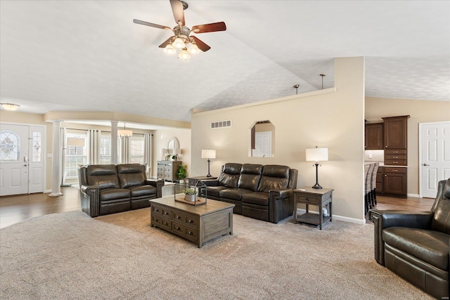 carpeted living area featuring visible vents, baseboards, ceiling fan, vaulted ceiling, and ornate columns