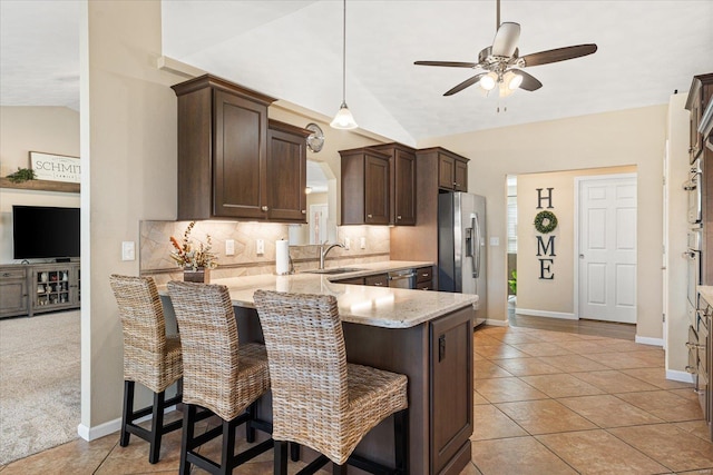 kitchen featuring vaulted ceiling, stainless steel appliances, backsplash, and dark brown cabinetry