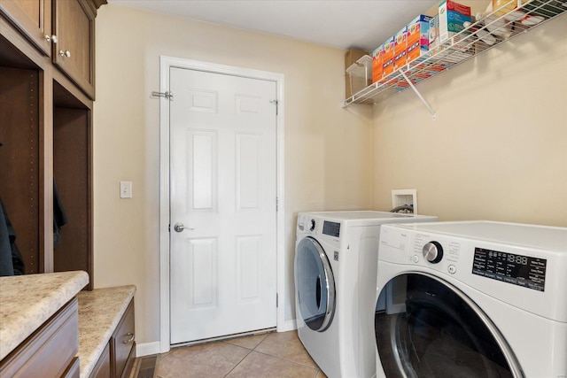 laundry area with light tile patterned floors, independent washer and dryer, cabinet space, and baseboards