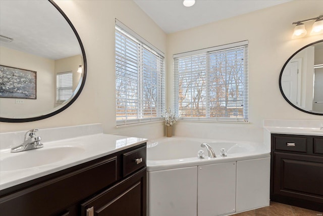 bathroom featuring two vanities, a sink, visible vents, and a bath