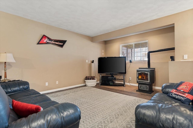 living area with a wood stove, baseboards, and wood finished floors