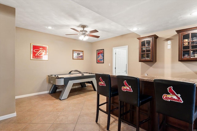 kitchen with baseboards, glass insert cabinets, a kitchen breakfast bar, a peninsula, and light tile patterned flooring