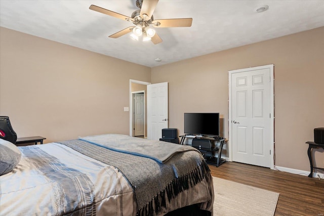 bedroom featuring a ceiling fan, baseboards, and wood finished floors