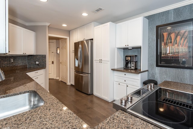 kitchen with dark wood-style floors, stainless steel refrigerator with ice dispenser, backsplash, white cabinetry, and dark stone counters