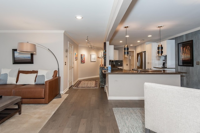 kitchen with dark wood-type flooring, freestanding refrigerator, ornamental molding, white cabinetry, and dark stone countertops