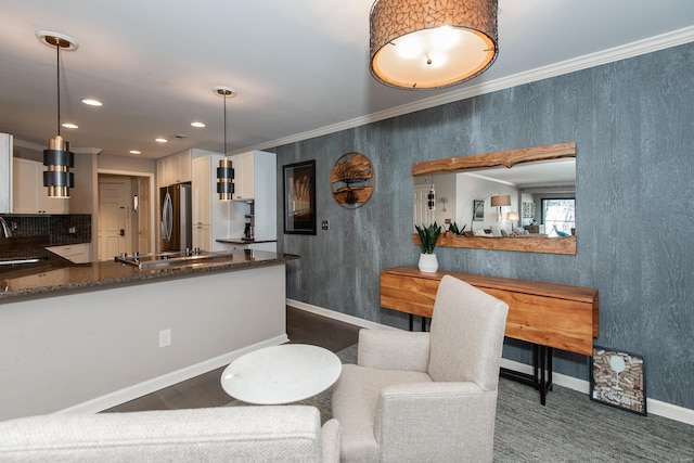 kitchen featuring freestanding refrigerator, white cabinetry, crown molding, and dark stone countertops