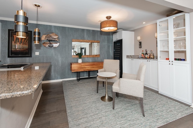 interior space featuring a dry bar, wallpapered walls, baseboards, ornamental molding, and dark wood-type flooring