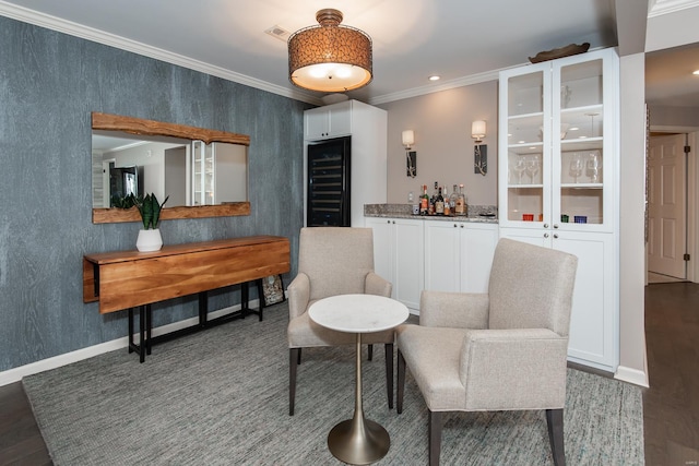 living area with beverage cooler, wood finished floors, baseboards, a dry bar, and crown molding