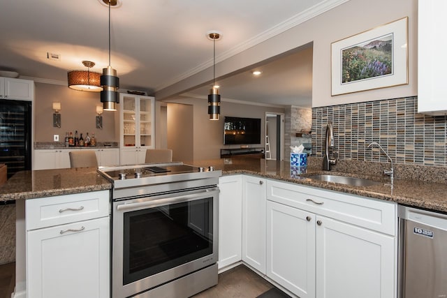 kitchen featuring ornamental molding, appliances with stainless steel finishes, dark stone countertops, and a sink