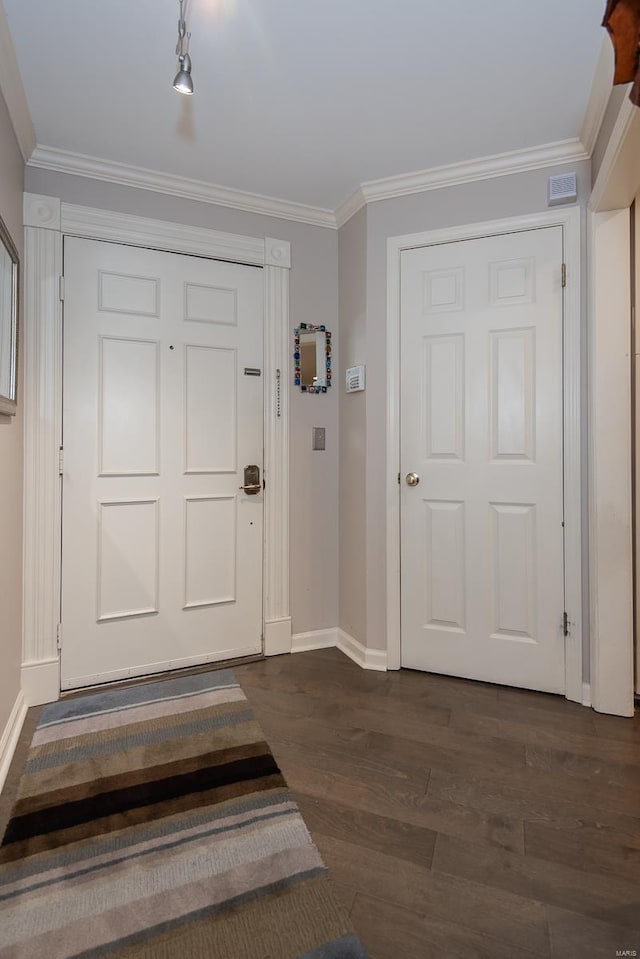 entryway with dark wood-type flooring, crown molding, and baseboards