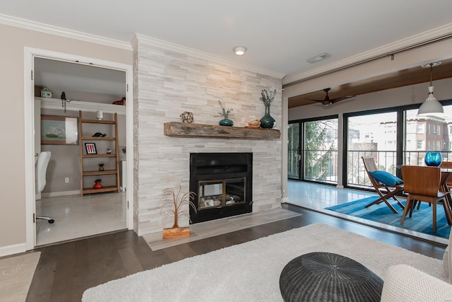 living area with crown molding, a fireplace, visible vents, wood finished floors, and baseboards