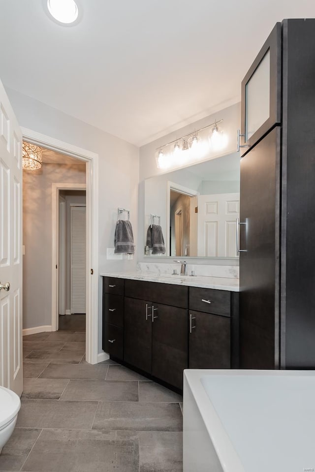 bathroom featuring toilet, vanity, and baseboards