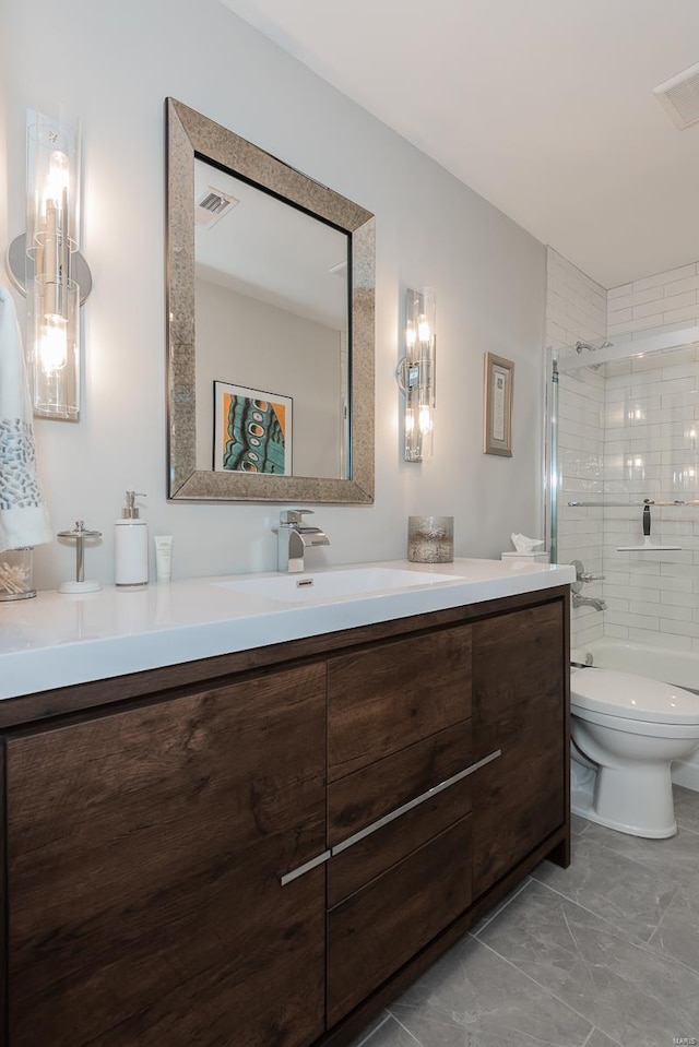 bathroom featuring toilet, vanity, a tile shower, and visible vents