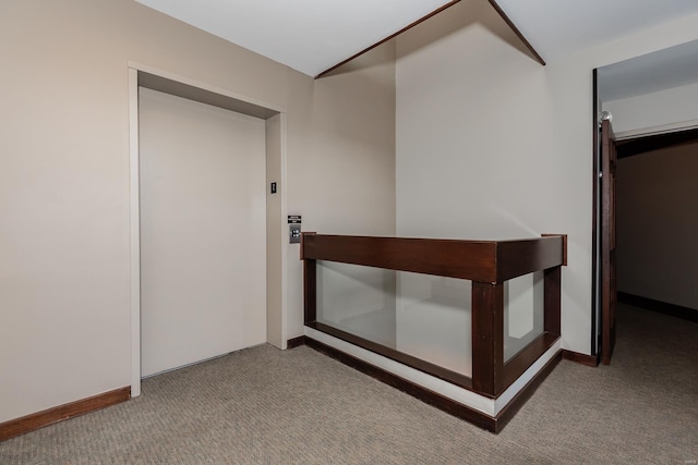 hall featuring elevator, carpet, and baseboards