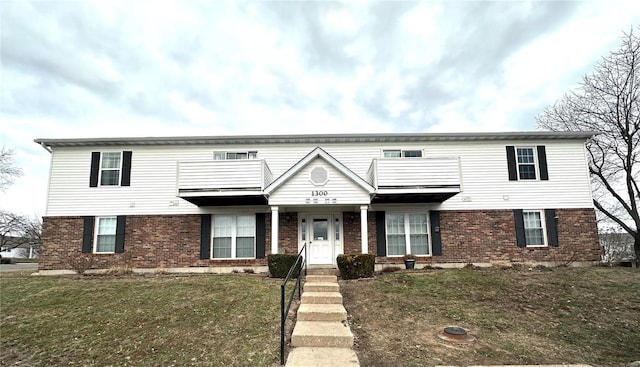 view of front of home with a balcony, a front lawn, and brick siding