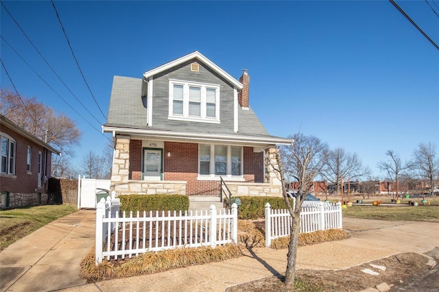 bungalow-style home with a porch, brick siding, driveway, stone siding, and a chimney