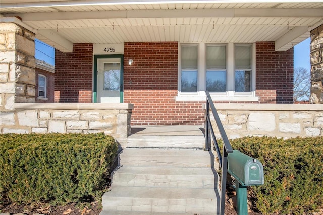 property entrance with covered porch and brick siding