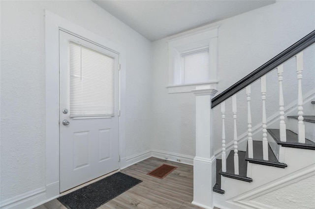 foyer with stairway, wood finished floors, and baseboards