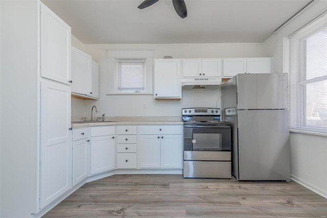 kitchen featuring light countertops, appliances with stainless steel finishes, white cabinetry, a sink, and under cabinet range hood