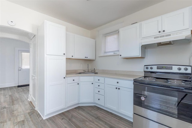 kitchen featuring under cabinet range hood, a sink, white cabinets, light countertops, and stainless steel electric stove