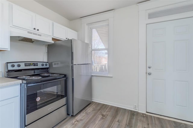 kitchen featuring under cabinet range hood, stainless steel appliances, white cabinets, light countertops, and light wood-type flooring