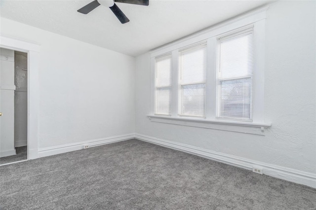 carpeted spare room featuring a ceiling fan and baseboards