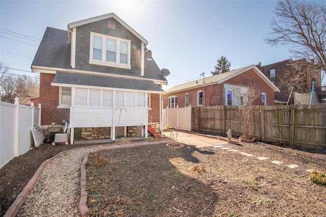 back of house featuring entry steps, a fenced backyard, and brick siding