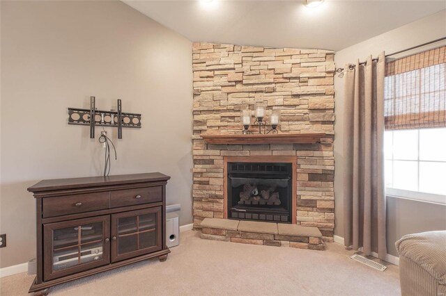 living area featuring baseboards, visible vents, a fireplace, and carpet flooring