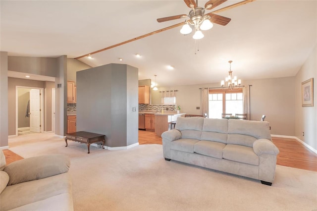 living area featuring vaulted ceiling, ceiling fan with notable chandelier, light colored carpet, and baseboards