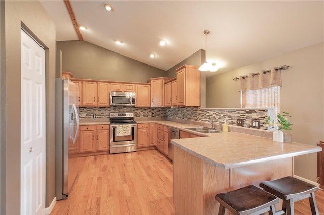 kitchen with stainless steel appliances, light countertops, light brown cabinets, and a peninsula