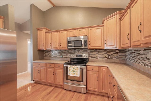 kitchen featuring light wood finished floors, lofted ceiling, stainless steel appliances, light countertops, and light brown cabinets