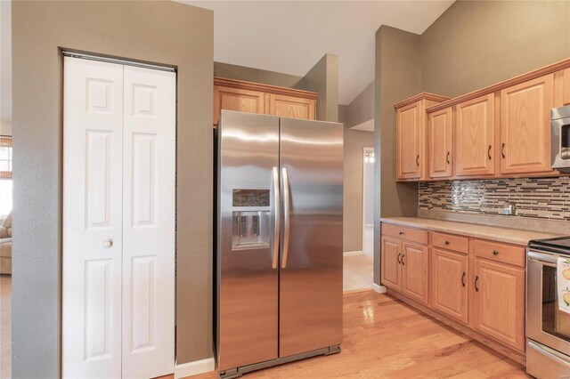 kitchen featuring tasteful backsplash, stainless steel appliances, light countertops, light wood-style floors, and light brown cabinets