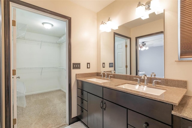 bathroom with a sink, a spacious closet, baseboards, and double vanity