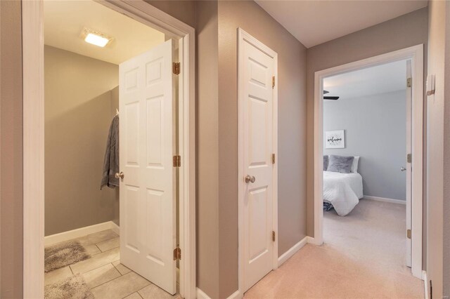 hall with light colored carpet, baseboards, and light tile patterned floors