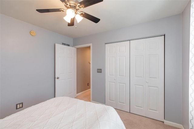 bedroom featuring ceiling fan, a closet, visible vents, and light colored carpet