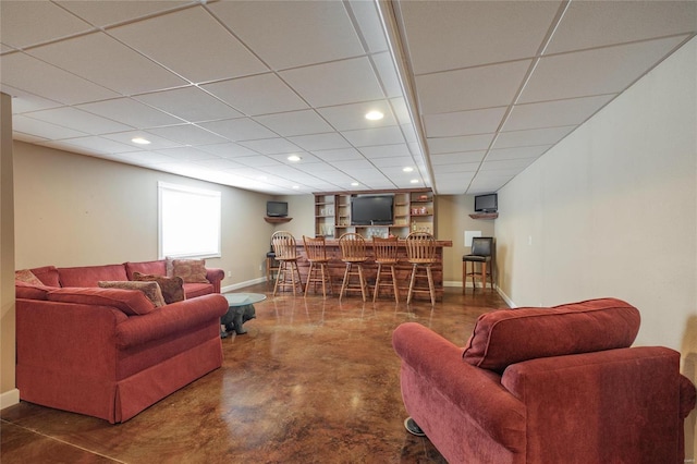 living room with recessed lighting, a bar, concrete flooring, a drop ceiling, and baseboards