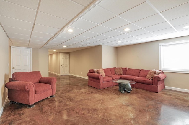 living room featuring a paneled ceiling, finished concrete flooring, baseboards, and recessed lighting