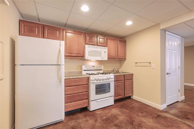 kitchen featuring white appliances, light countertops, a sink, and baseboards