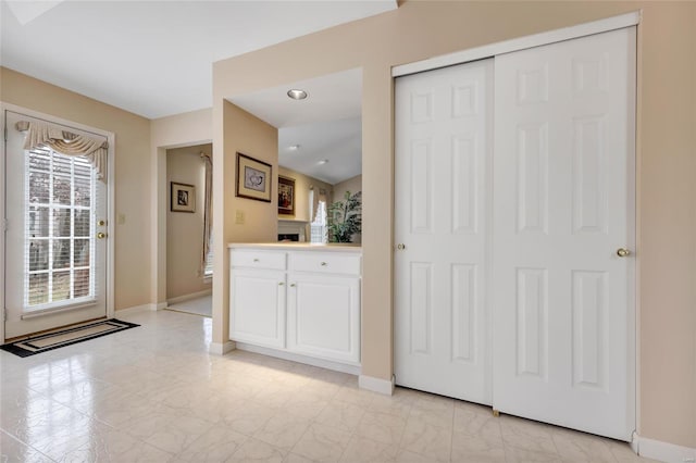 interior space with marble finish floor, a fireplace, light countertops, white cabinets, and baseboards