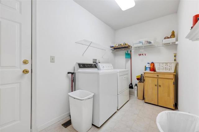 clothes washing area with cabinet space, baseboards, and separate washer and dryer