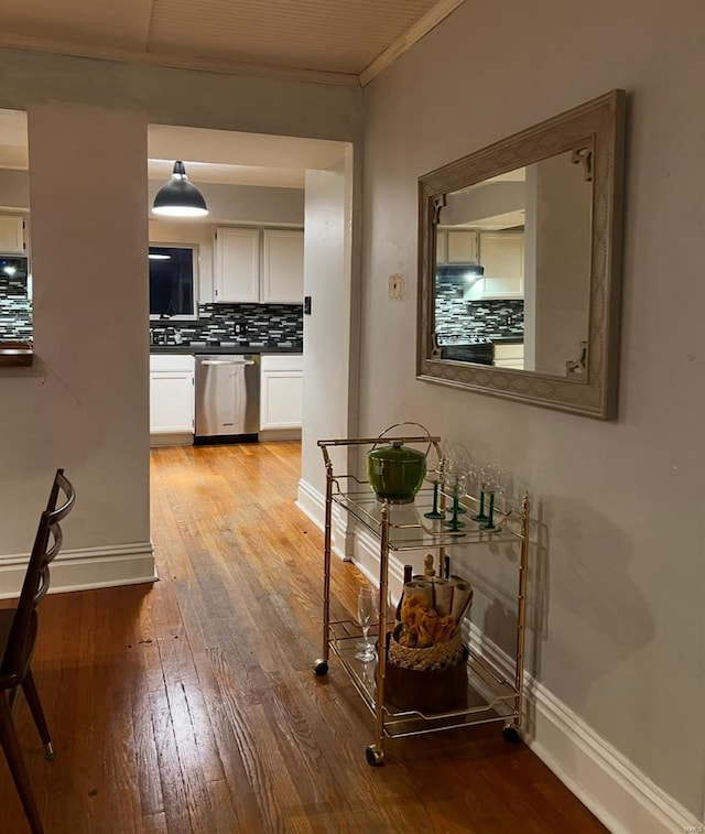 hallway featuring ornamental molding, light wood-style flooring, and baseboards