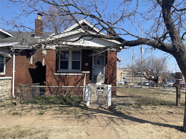 view of front of house with brick siding, a fenced front yard, and a chimney